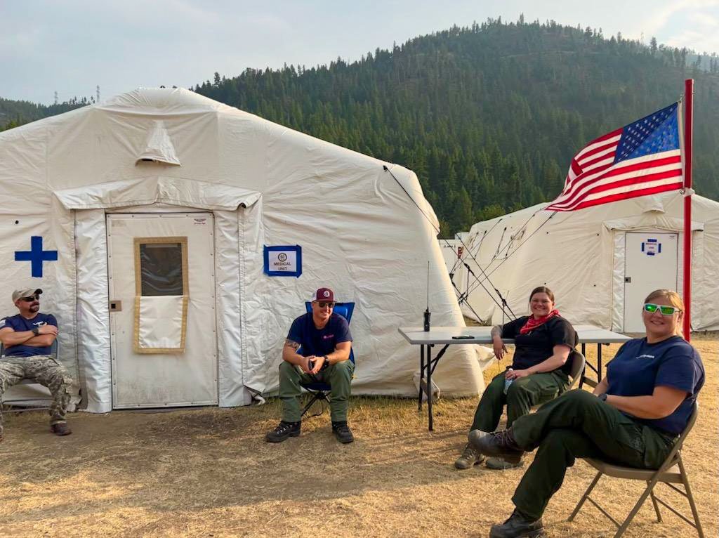 EMT Deployment team sitting at camp with tents behind them